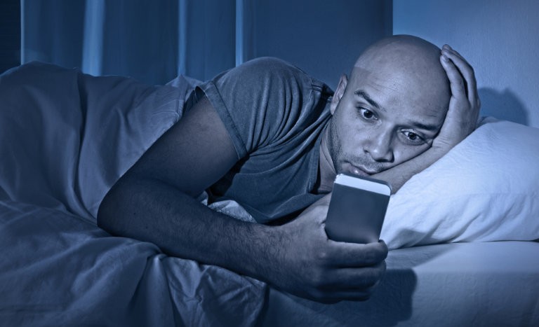Man reading ebook on smartphone at night